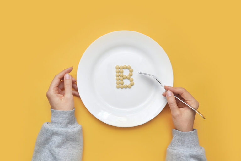 Sign of vitamin “B” out of pills on a white plate. Vitamin “B” d